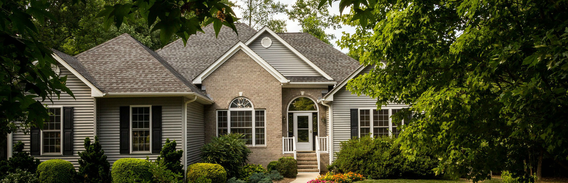 A single-family house with a front lawn and mature trees