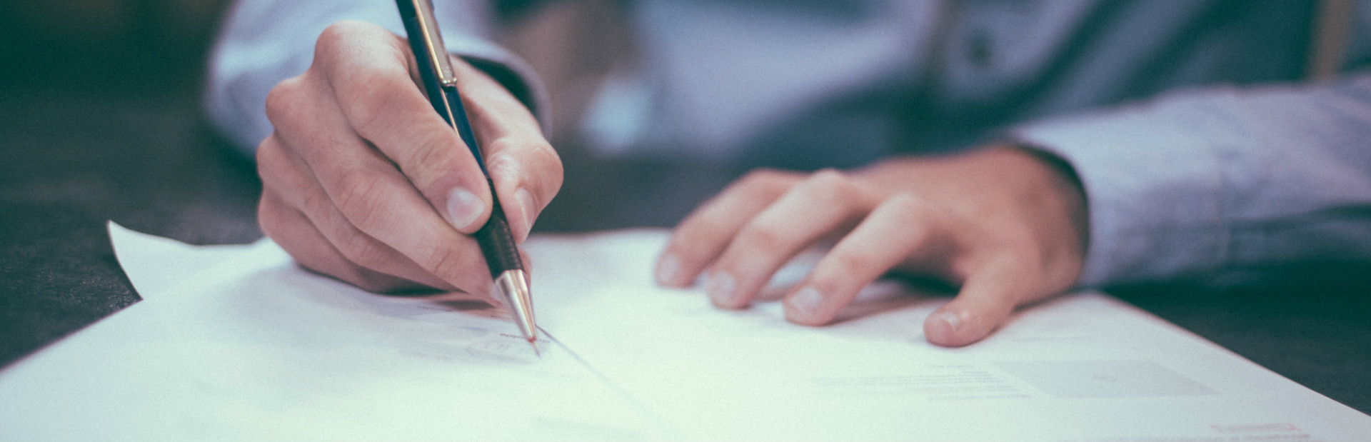 A hand signing a document with a fountain pen